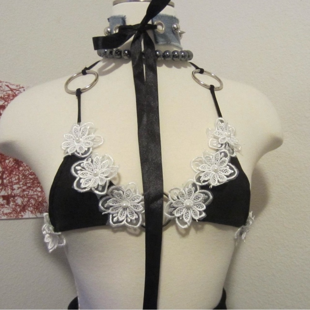small bikini top 🤍 ♻️ It features a white flower pattern 
with metal rings